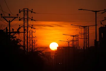 Power transmission towers silhouetted against a sunset