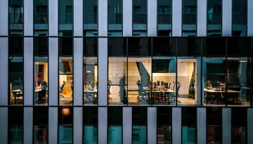 Lighted office windows in a modern glass building facade at night